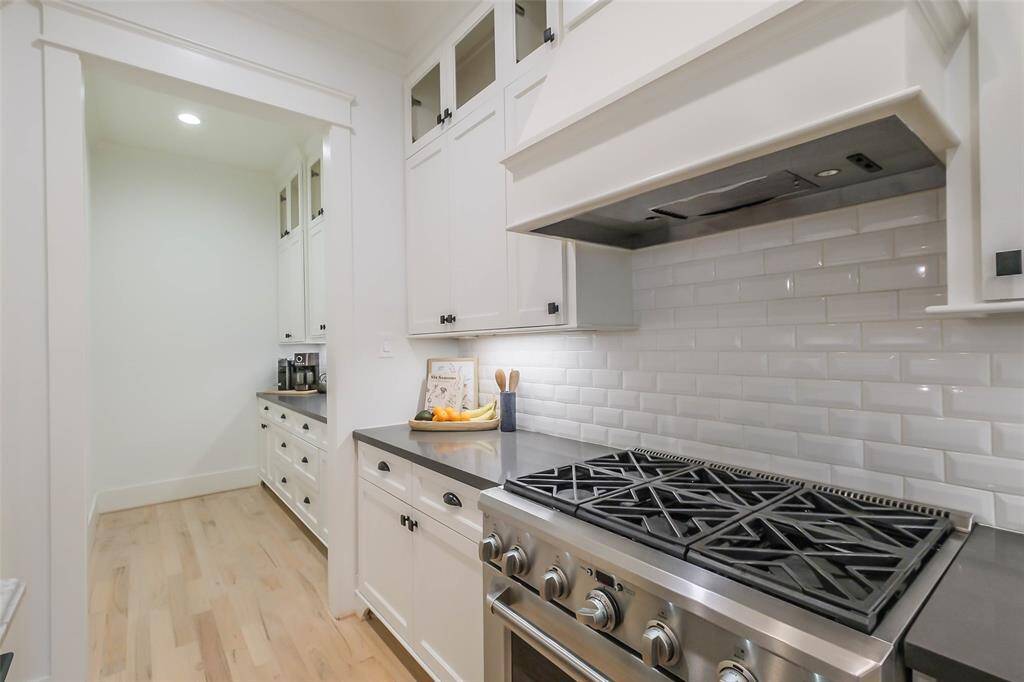 This photo showcases a fabulous stainless steel 6 burner gas stove. The design is clean and elegant, featuring ample counter space and upper cabinets with glass fronts.