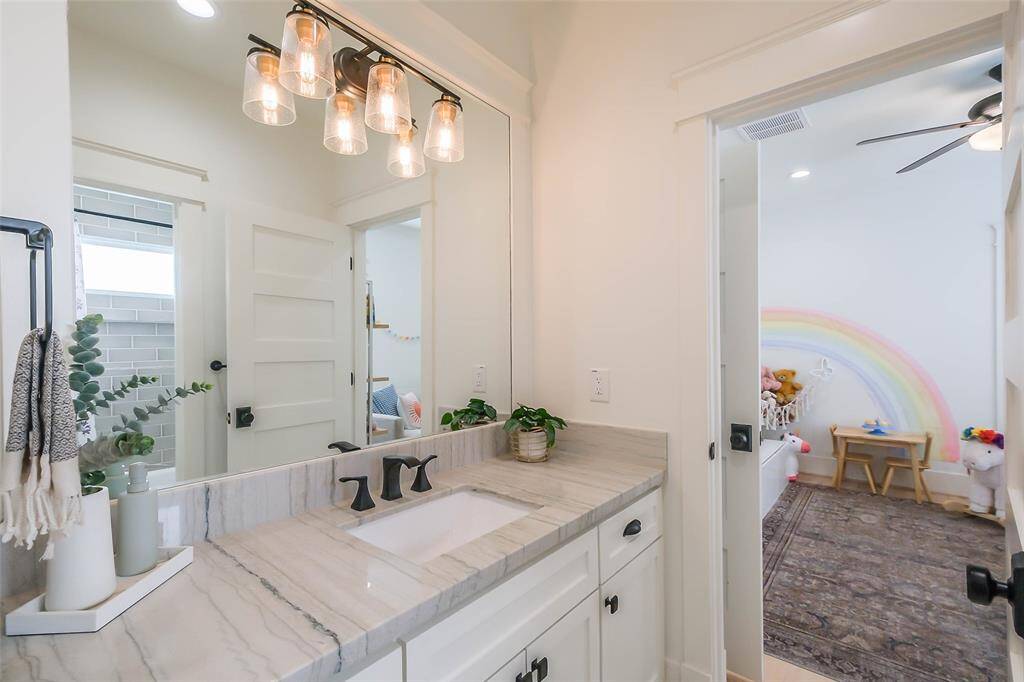 Upstairs secondary bathroom connects both bedrooms and features the same sleek countertops, fixtures and lights.