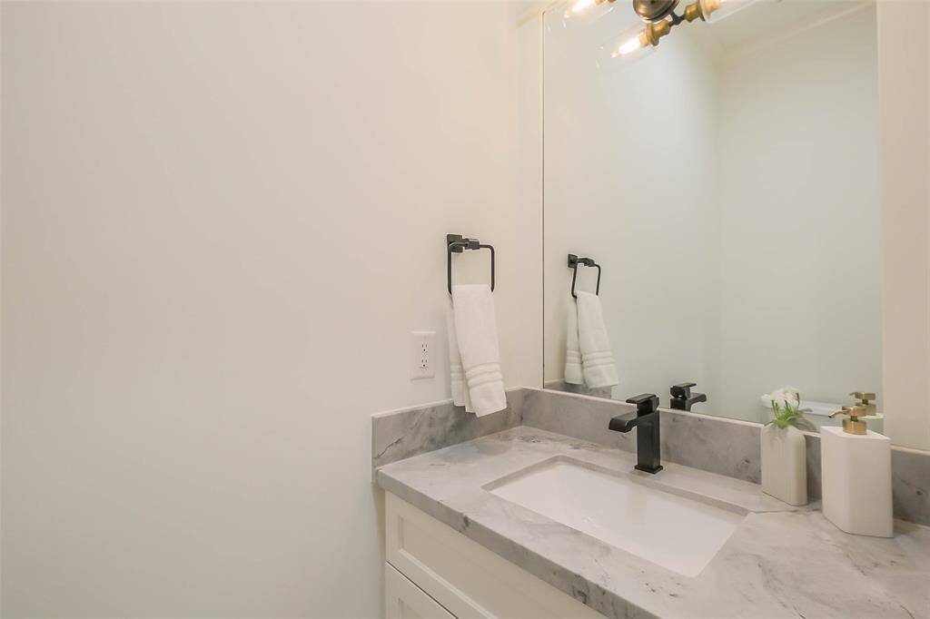 Guest half bath on the first floor features modern countertop and a black faucet.