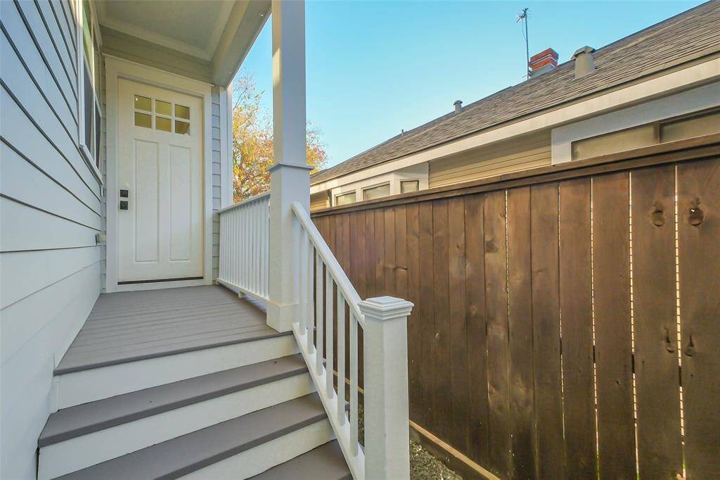 Welcome home!  Entry features a covered porch with a white door and railing, leading up a set of stairs. It features a clean, modern exterior alongside a wooden privacy fence.