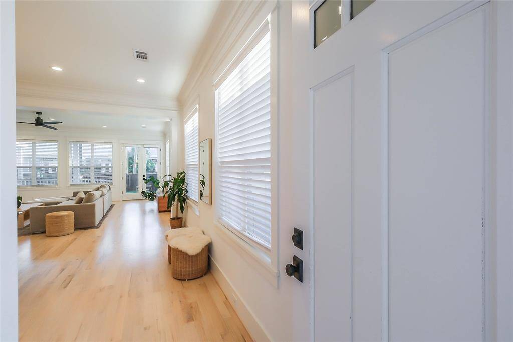 Bright and inviting entryway leading to a spacious living area with light hardwood floors, large windows. Perfect for natural light lovers.