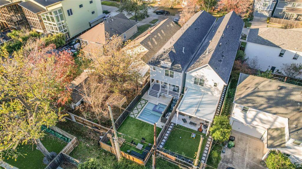 This aerial view showcases this modern two-story home with a perfectly manicured Turf backyard featuring a patio and pool area.