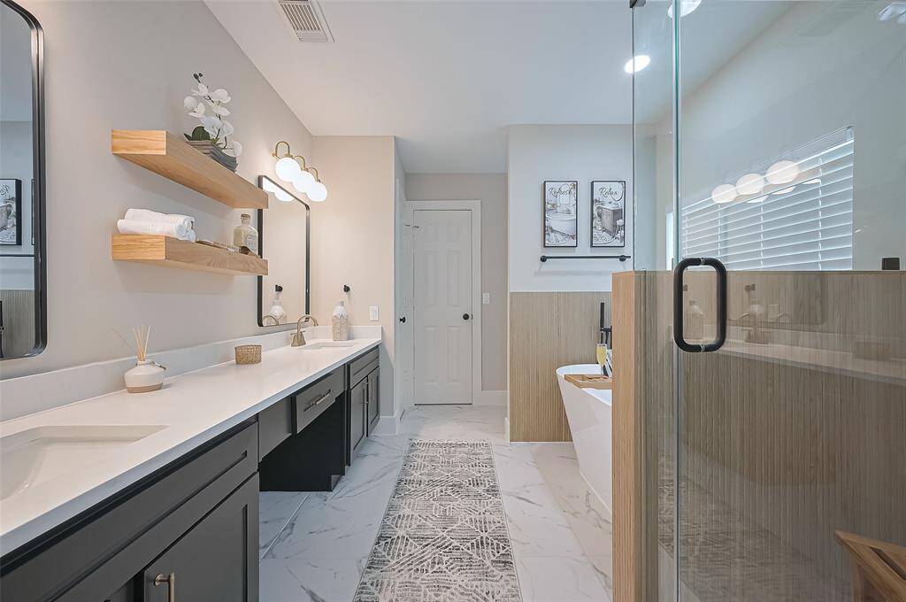 Resort style primary bathroom ensuite featuring a free standing soaking tub, spa-like walk in shower with designer finishes, upgraded tile flooring, stylish new lighting, & quartz counters! Offers plenty of storage and fantastic walk-in closet!