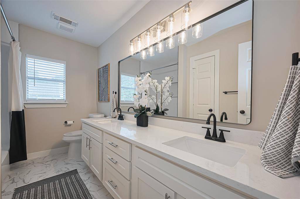 Remodeled secondary bathroom with double quartz vanity, designer finishes and clean line, modern tile design in shower/tub!