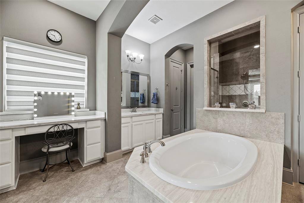 Hotel spa like primary bathroom featuring two sinks, vanity area, soaking tub, and generous in size.