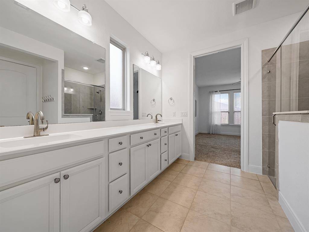 En suite bath complete with double sinks, large vanity, and plenty of storage.