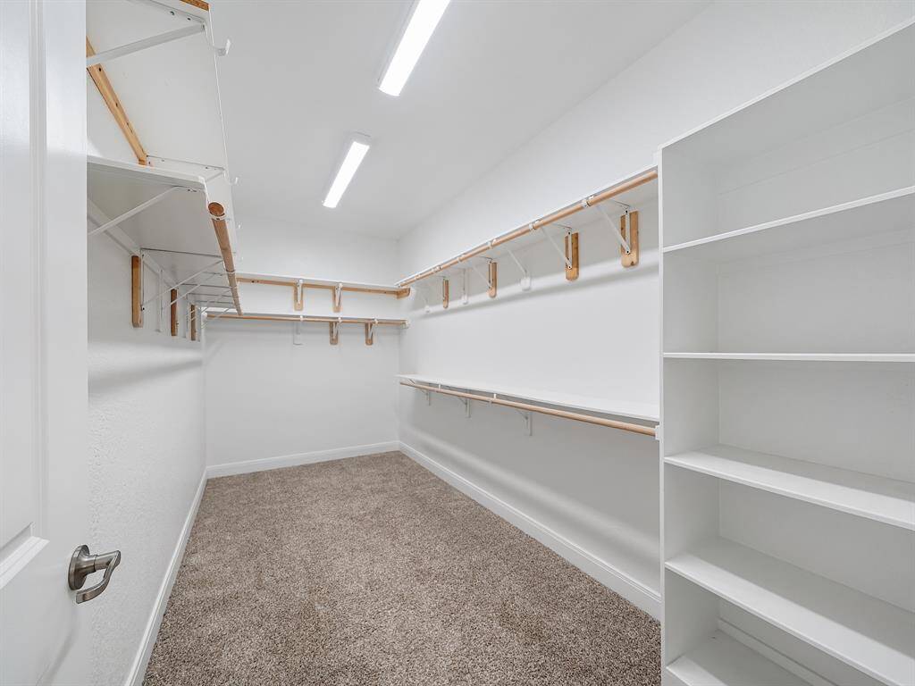 HUGE walk in closet with built-in shelving, multi-level clothing racks.