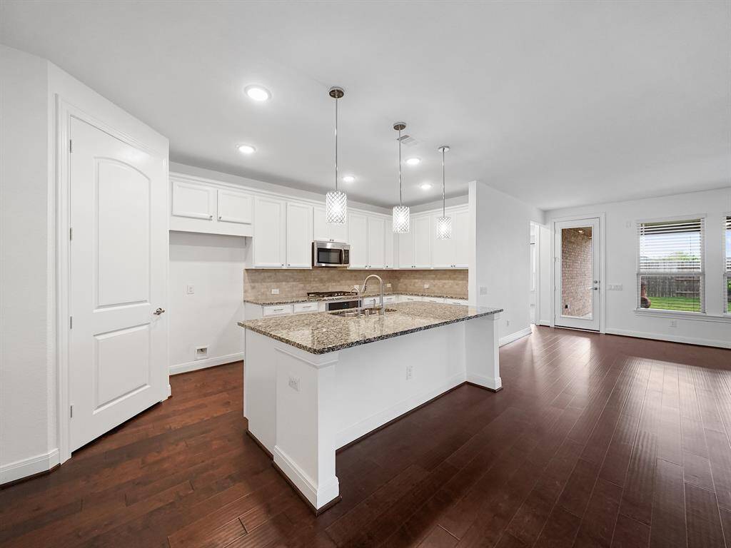 Bright white kitchen with granite countertops and coordinating backsplash.  Oversized island with breakfast bar is the perfect place for smaller meals.