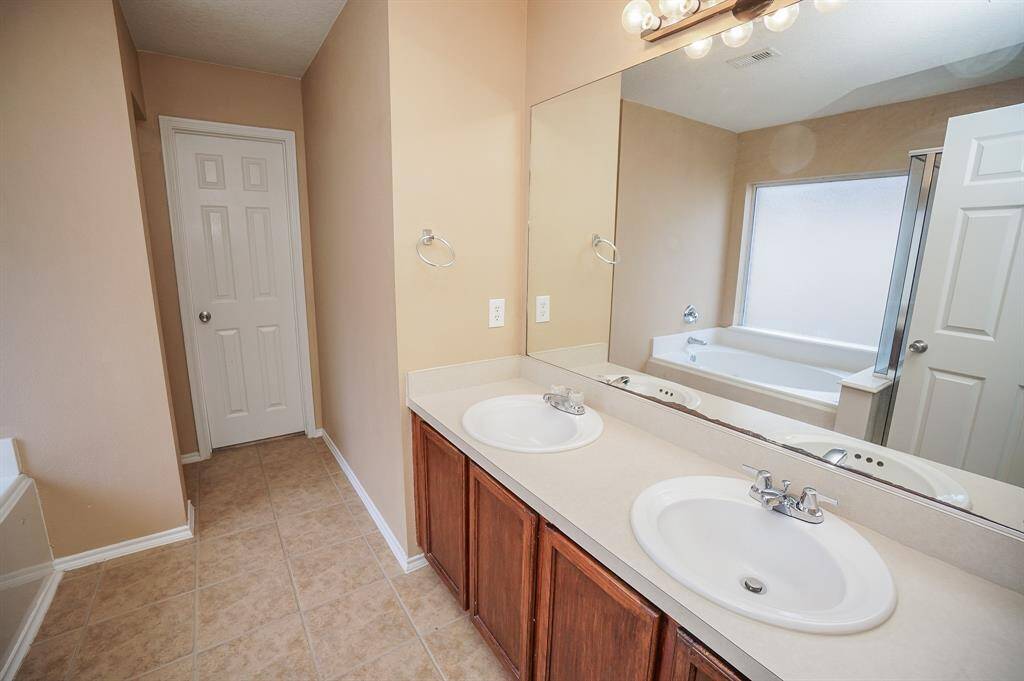 Your primary ensuite bath is relaxing, with traditional cabinetry below the dual-sink counter top. The wall-wide mirror makes the space look even bigger!