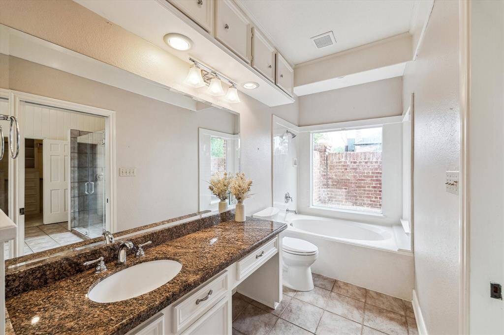 The second half of the primary bathroom includes a seated vanity area with a soaking tub.