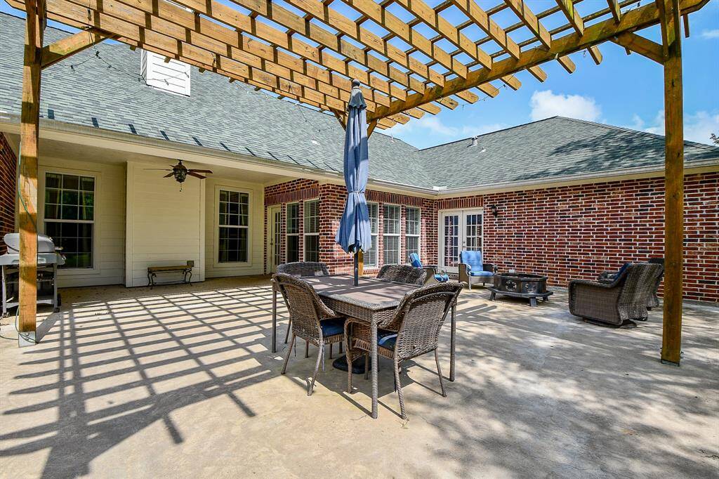 This spacious backyard features a large patio area with a wooden pergola, perfect for outdoor dining and relaxation.