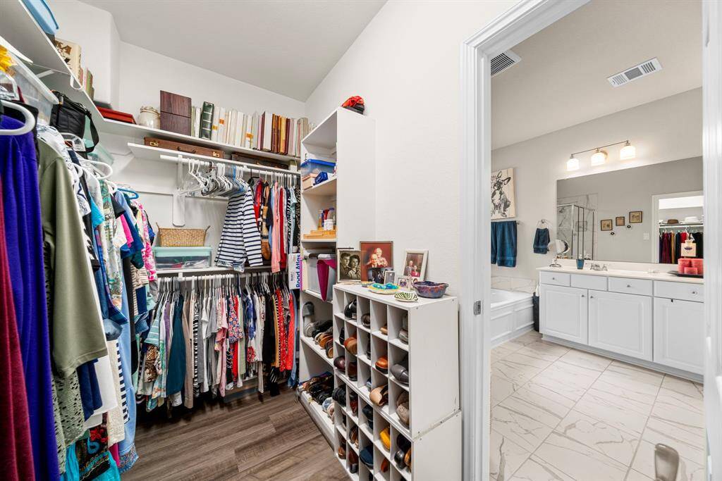 Primary En-suite Walk-in closet.  Note: upgraded storage shelves in and upgraded hanging rods allowing for layered hanging space for maximizing storage of clothes and apparel by allowing both long and short items to be hung efficiently, expanding the capacity of the space.