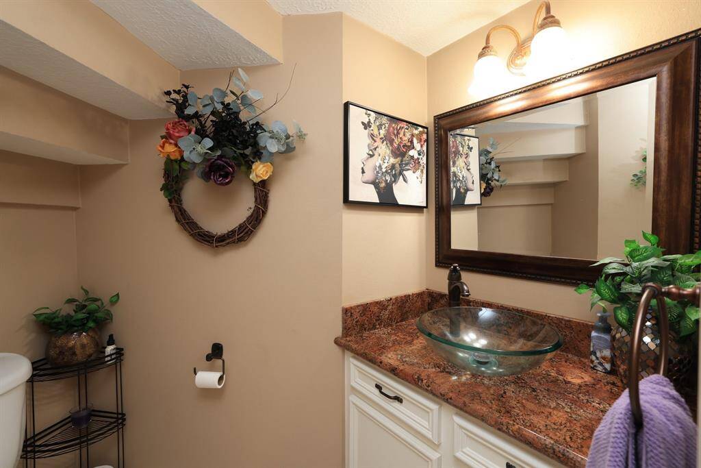 The half bath is located under the staircase and just off the entry and living room.  Granite counters and vessel sink with tile flooring.