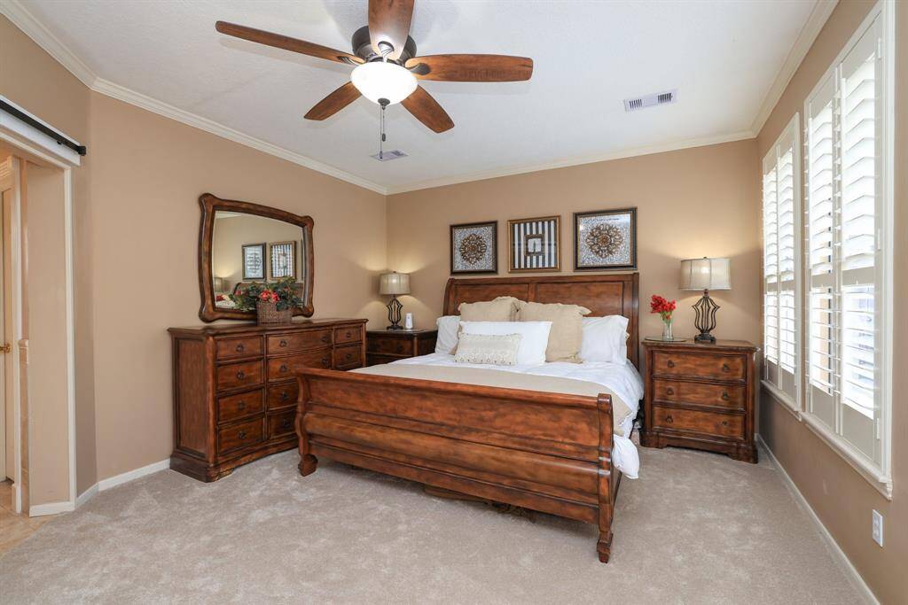 The Primary suite is located in the back of the house and has an amazing view of the pool.  Plantation shutters and plush carpeting!  The Master Bath is just to the left.
