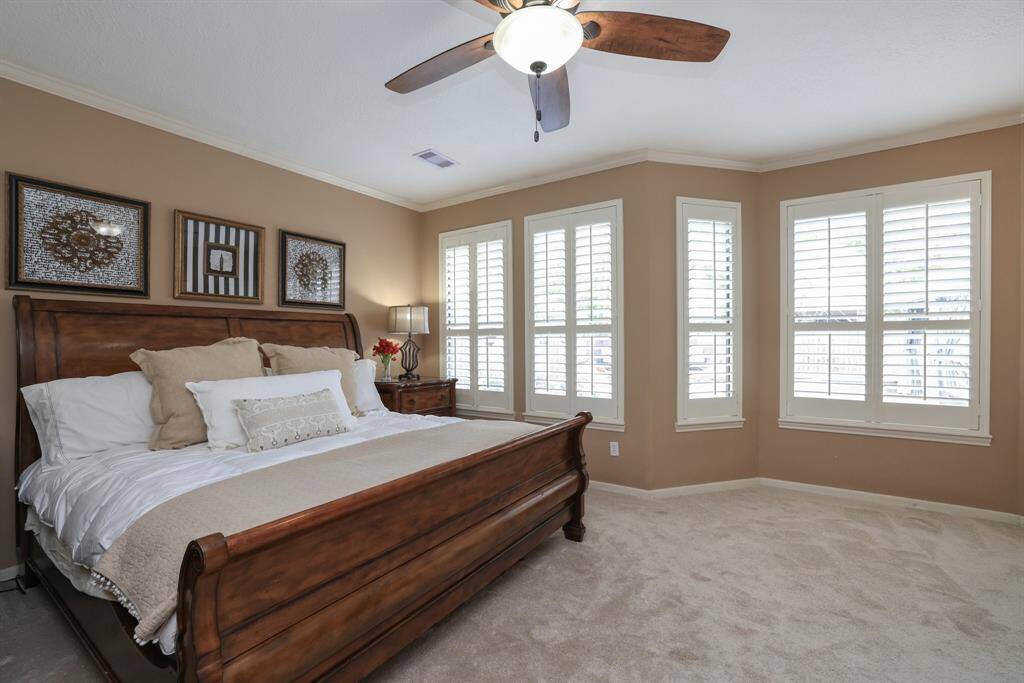Another view of the Primary bedroom with lighted ceiling fan.  Direct access to the pool is through a French door that opens to the pool area.