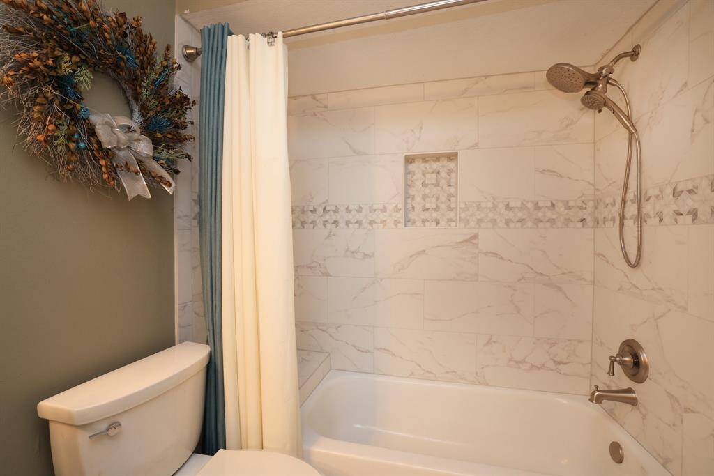 A close up of the quartz stone in the shower with handheld shower faucet.