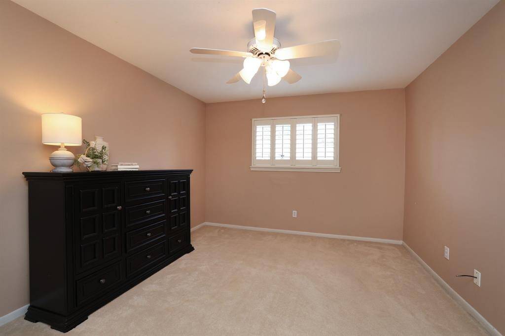 One of three bedrooms on the second floor with plush carpet and ceiling fan.