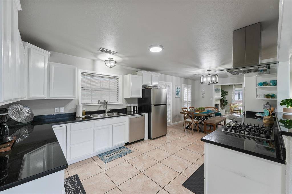 The kitchen boasts extensive counter space, white cabinetry, and stainless steel appliances, all flowing effortlessly into the dining and living areas.