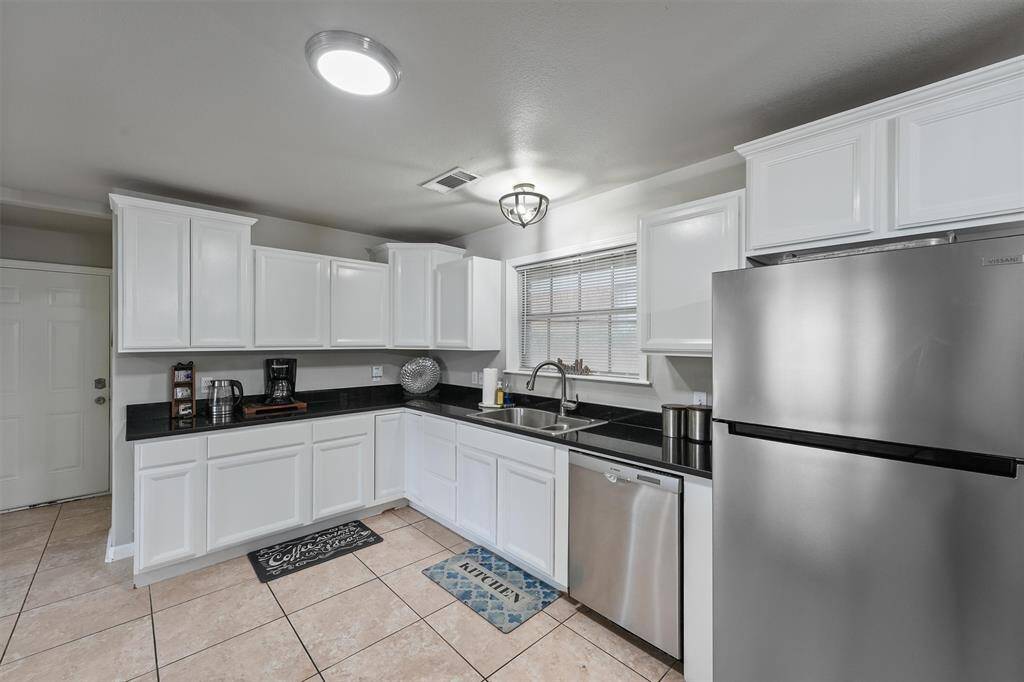 Clean and classic, this kitchen offers plenty of storage and prep space with granite countertops and tile flooring.