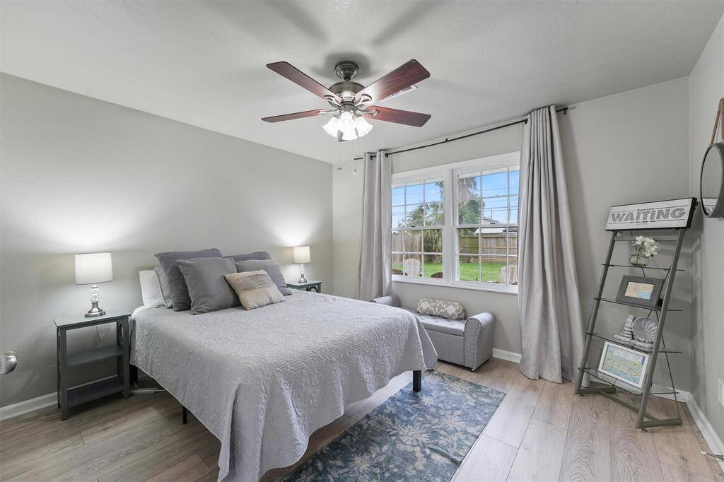 A serene bedroom with soft natural light and backyard views offers the perfect place to unwind.