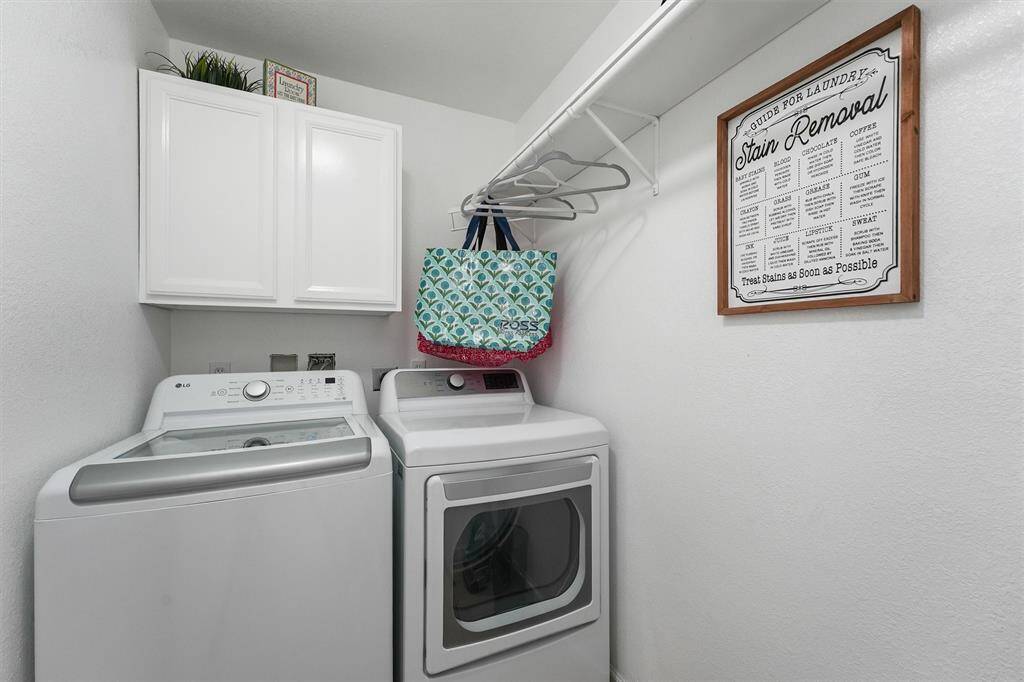 A tidy laundry room with upper cabinets and hanging space keeps everything organized and out of sight.