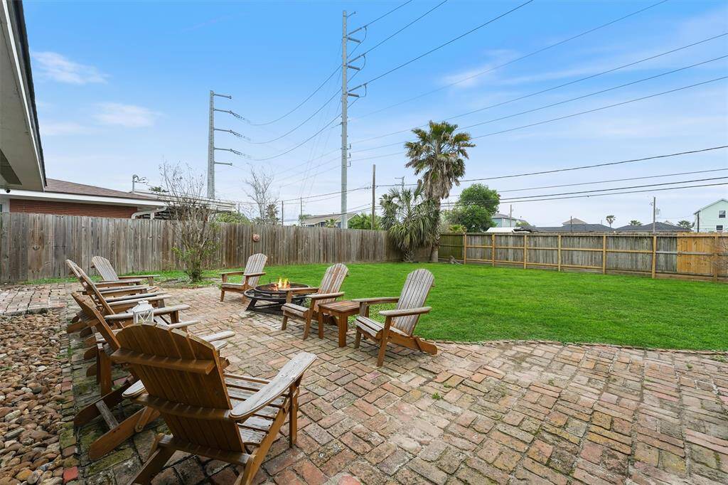 The large backyard is fully fenced with a charming brick patio and fire pit—perfect for outdoor entertaining.