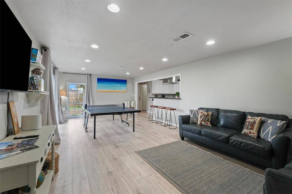 This oversized bonus room, currently set up for ping pong and lounging, connects effortlessly to the kitchen with bar seating and backyard access.