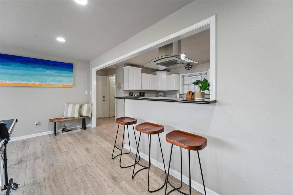 A sleek bar connects the kitchen to the living space, offering a casual spot for breakfast, snacks, or chatting with the cook.
