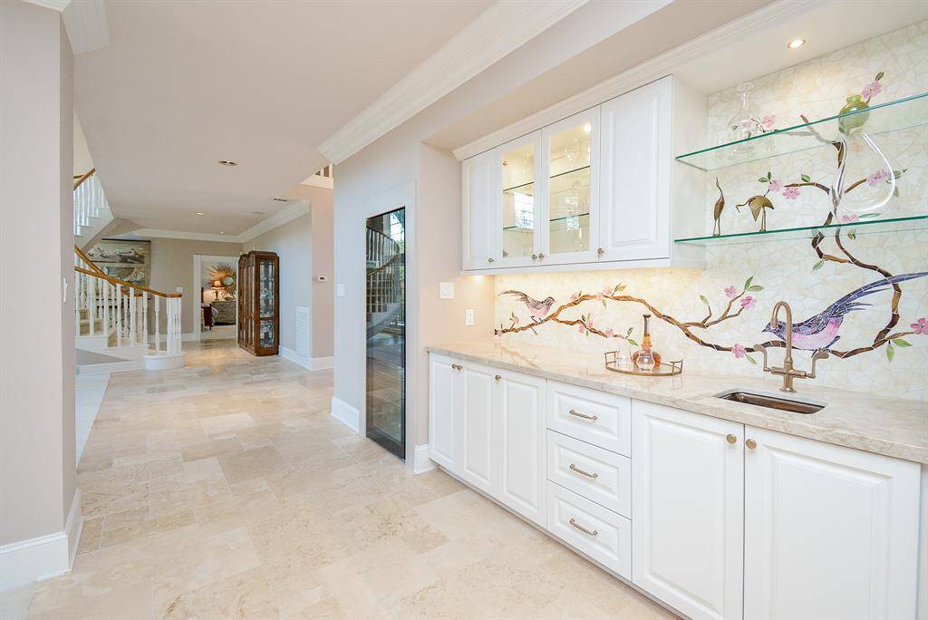 This photo showcases a the 120 Bottle Wine Cooler and Elegant Wet Bar, featuring Custom Built-In Cabinetry with Glass Shelves and Elegant Lighting.
