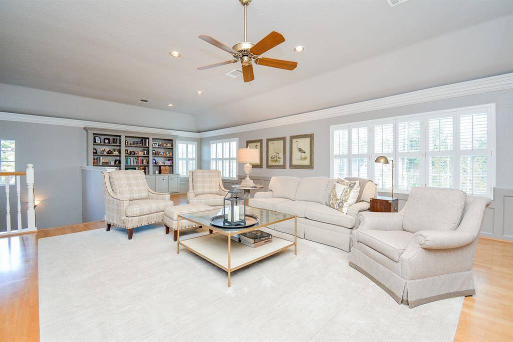 This space features a spacious, light-filled area with a wall of built-in bookshelves, Wainscoting and a window with Plantation Shutters. It's versatile space that is currently set up as an exercise space with a bench, and offers potential for a second home office or library.