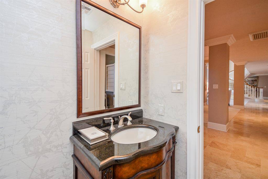 This photo showcases a bright and functional laundry room with room for a Freezer also offers Granite Countertops, a Sink, Ample Cabinetry, and a Arched window for natural light.