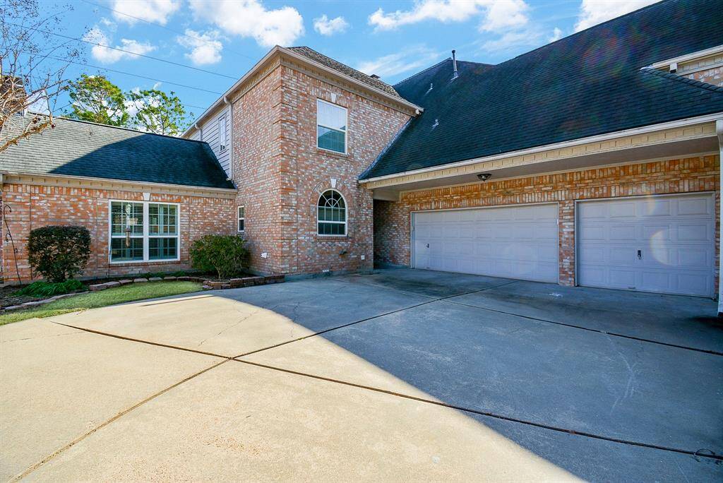 This inviting backyard features a spacious paved patio area surrounded by mature trees and a wooden fence for privacy, perfect for outdoor entertaining and relaxation.
