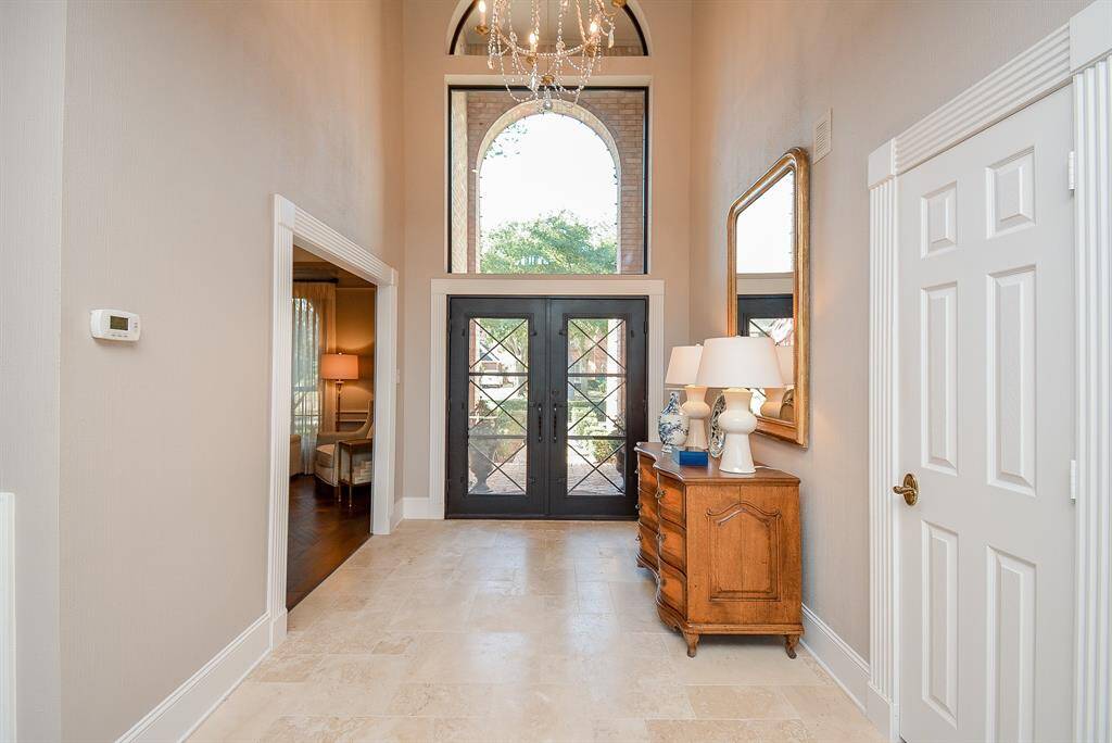 This photo showcases a bright, Open-Concept area with Travertine Flooring, High Ceilings and a Large Wall of Windows offering an elegant and welcoming atmosphere.
