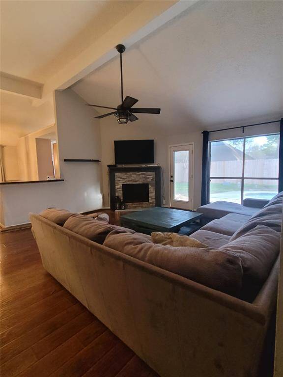 This inviting living room features high ceilings and a cozy fireplace. Natural light streams through the patio door and window, offering a view of the backyard. The space is open to the kitchen, enhancing the home's flow and functionality.
