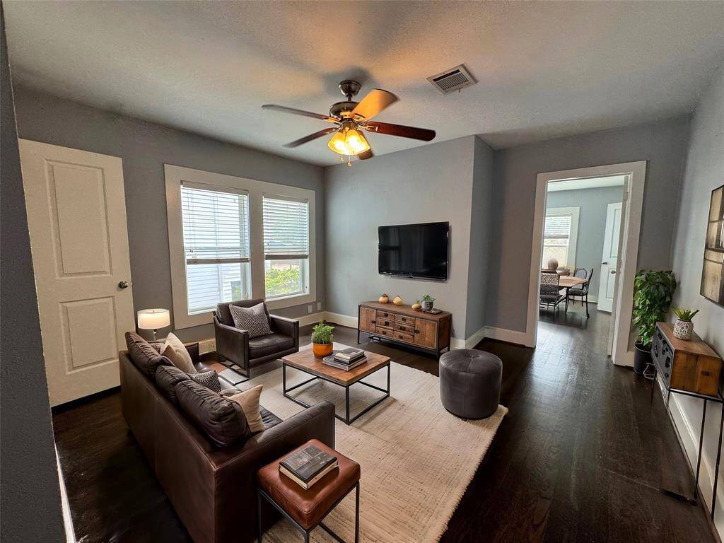 Living room space features hard wood floors and lots of natural light. Plenty of storage space. AI Staged