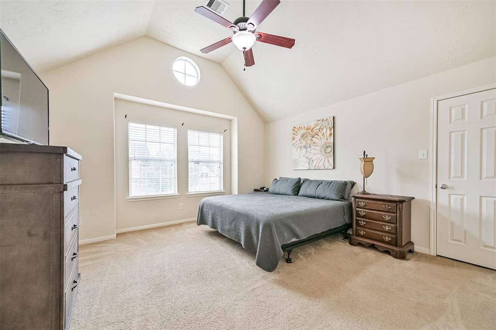 Spacious primary bedroom feathring high ceilings and large windows that bring in plenty of natural light, creating a relaxing retreat.