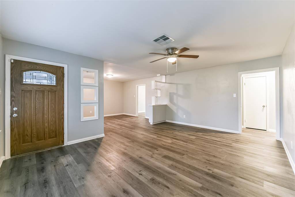 Large living room has ceiling fan and vinyl plank flooring