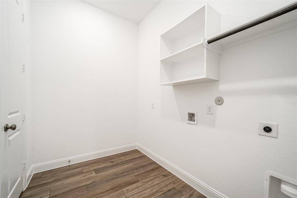 The utility room has vinyl plank floors, shelves, hanging space, and a storage closet.
