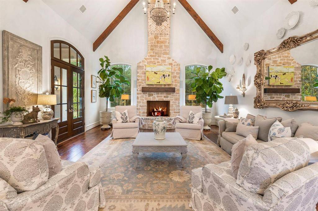 View of the architectural masterpiece from the kitchen. Stone fireplace, French doors, and beautiful wood floors