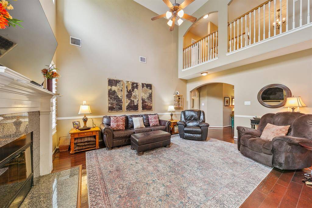 Timeless family room with soaring ceilings, arched openings and continuous wood planked flooring for seamless transitions between spaces.