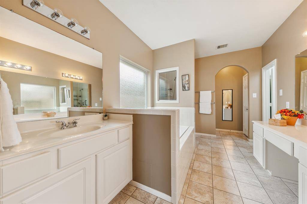 Photo showing second sink, soaking tub, private water closet at the far end and large walk-in closet accessed through the door at the right.