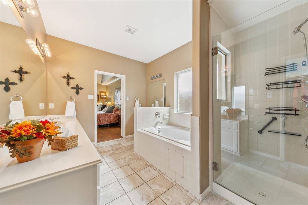 Photographed from the far end of the primary bath, showing second soaking tub and separate glass shower.
