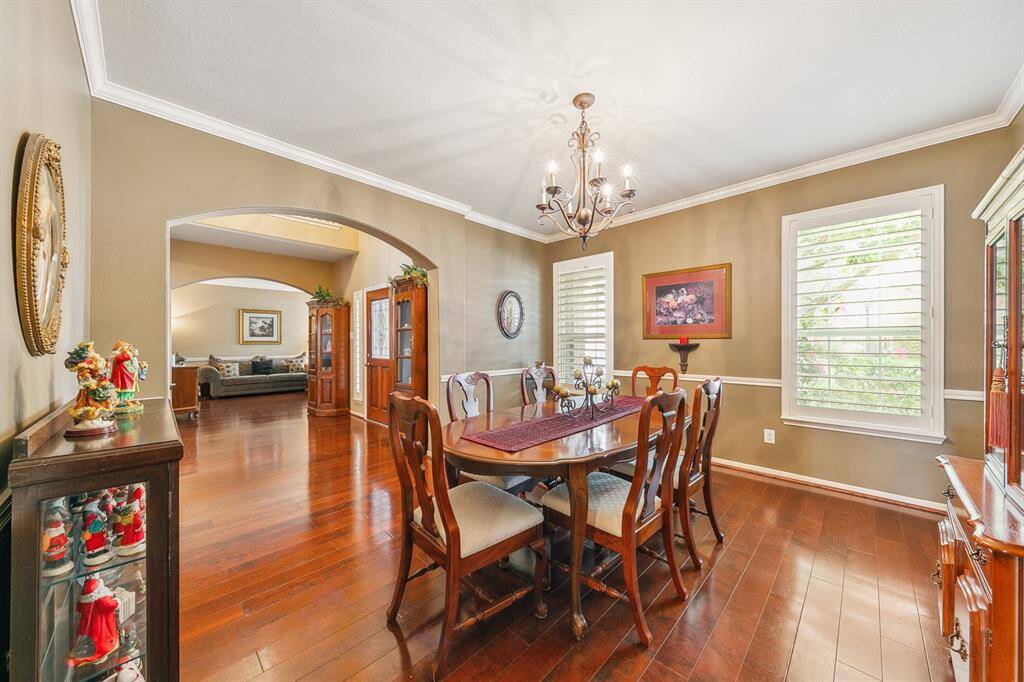 View from the dining room across the foyer to the sitting area!  Lovely details include warm wood floors, crown molding and custom wide plank shuttered windows!