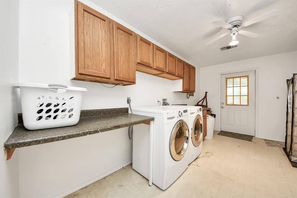 This is a spacious laundry room, ample countertop space for folding, and wooden cabinets for storage. A ceiling fan and an exterior door provide ventilation and easy outdoor access.