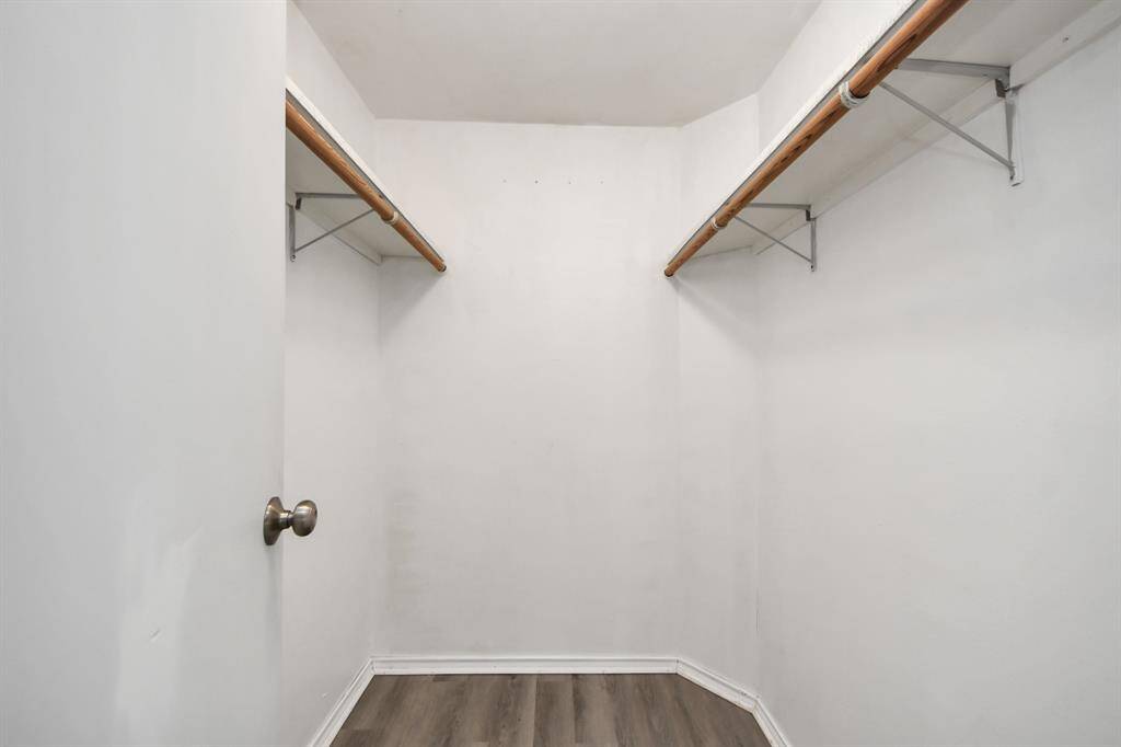 This is a spacious walk-in closet with two long hanging rods and a clean, minimalistic design. The walls are painted white, and it features a neutral-toned floor. Ideal for organizing clothing and accessories.