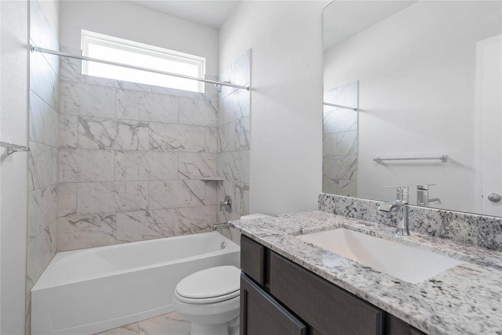 Another view of the primary bathroom which features a large walk-in shower with tile surround, garden tub to soak after a long hard day, large rainglass window allowing in the natural light, custom paint, sleek and dark modern finishes.