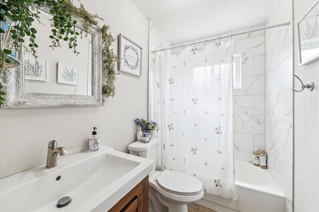 Updated primary en-suite is luxurious with new vanity, window, and shower/tub combo with tile surround.