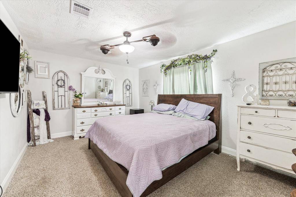 Primary bedroom offers plenty of space, plush floor covering, and double ceiling fan.