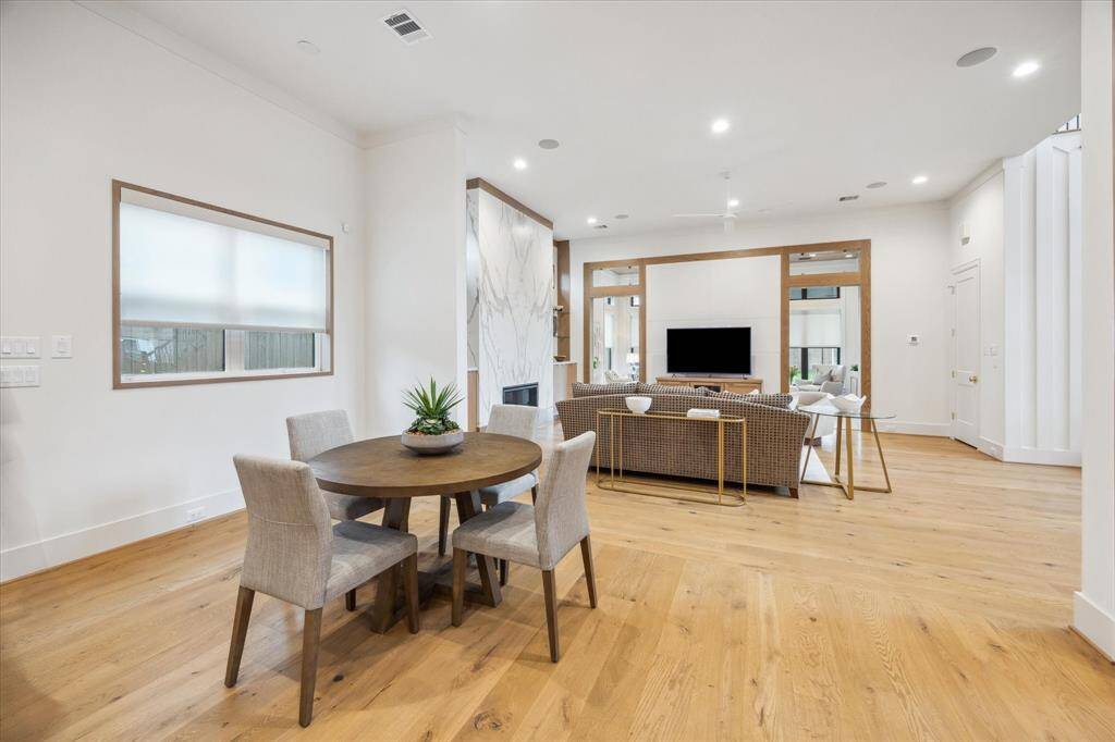Just past the dining room is the kitchen and adjacent breakfast space.  Breakfast light and pendant fixtures over the island are by Hudson Valley Lighting.  Counters and waterfall island are quartz, appliances are Thermador. Notice the white oak wood window trim carried throughout these spaces as well.