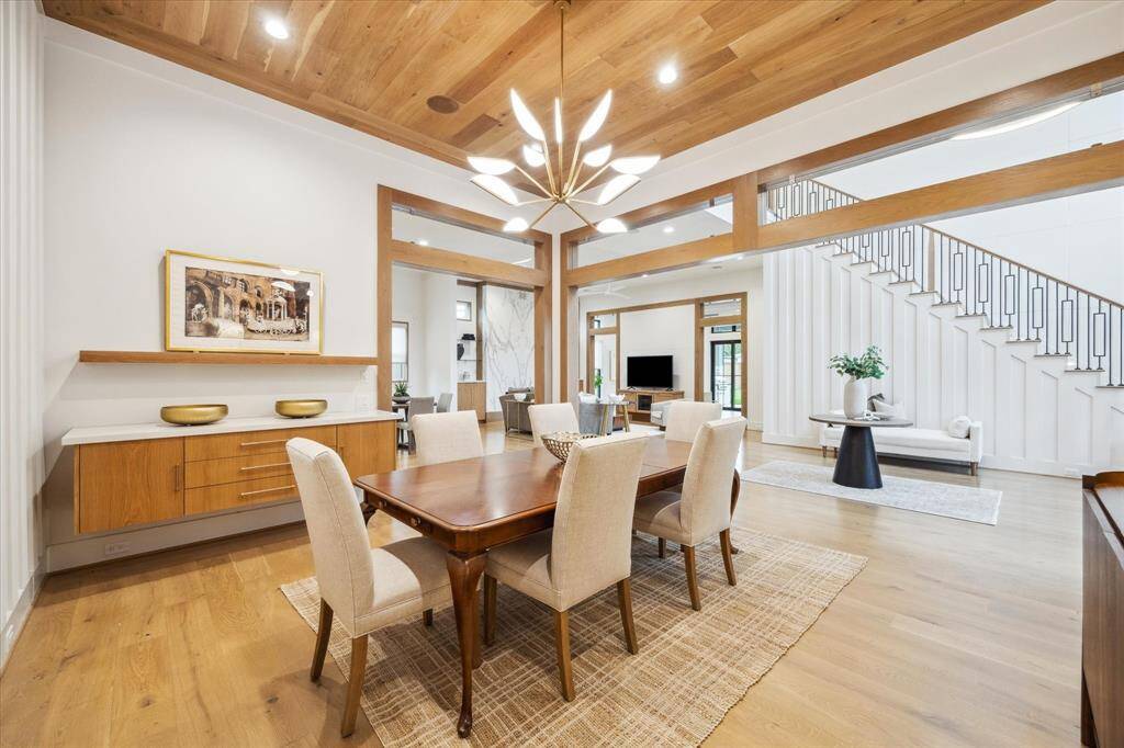 High ceilings, dramatic lighting, and white oak wood ceiling detail, along with matching wood casing and transoms, highlight the extra detail given to this dining area. Notice the floating buffet & shelf on the far right wall.